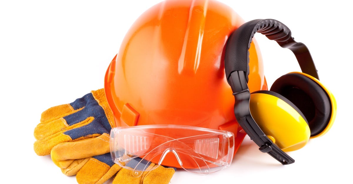 An orange hard hat, yellow gloves and ear muffs, and safety glasses lay in a pile against a white background.