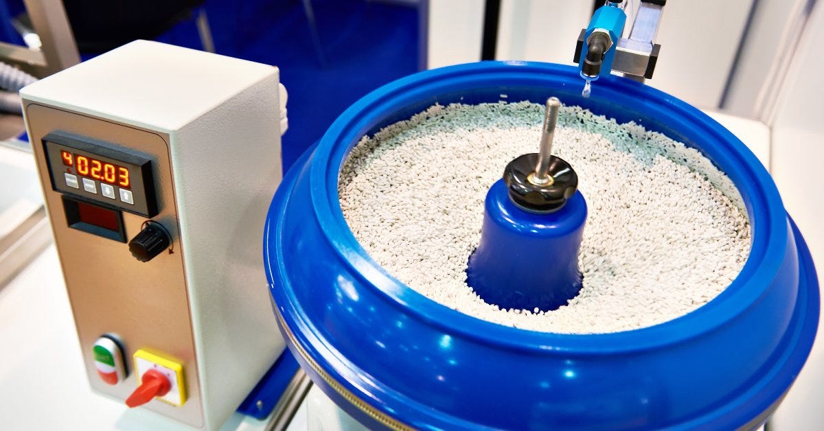 A control panel with a digital reading operates a blue rock polishing tumbler. The machine is filled with polishing media.