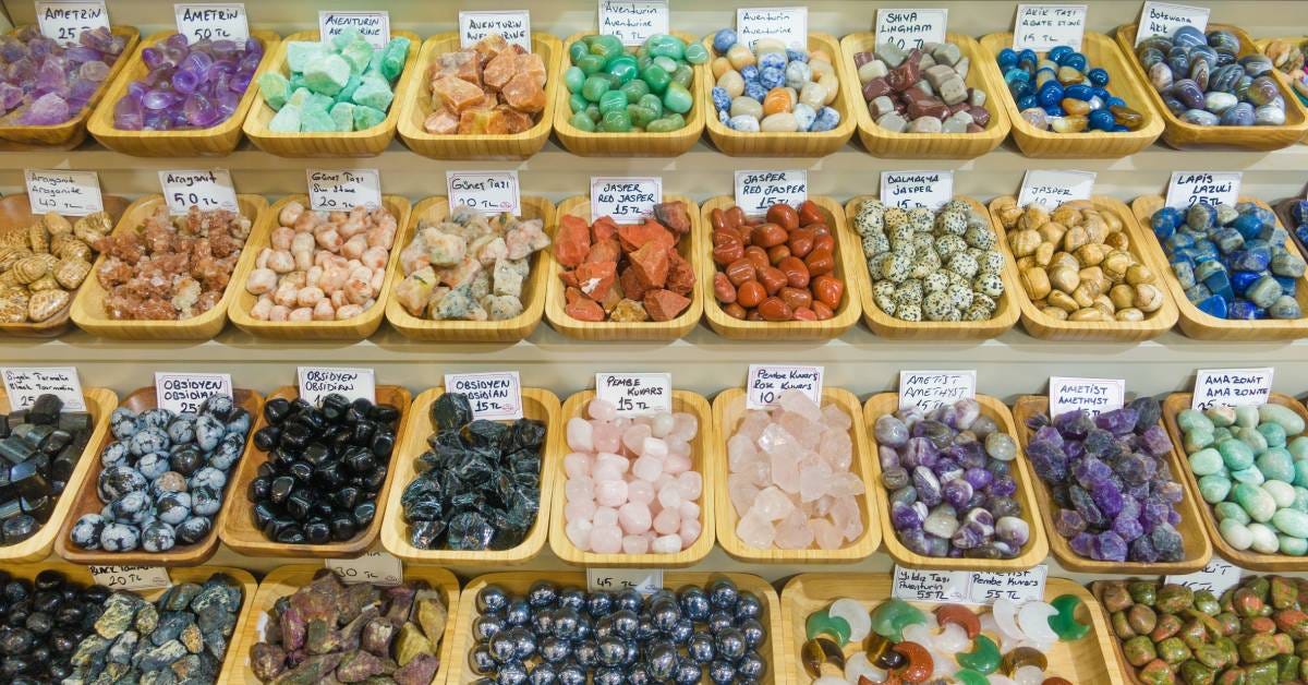 Multiple small yellow baskets lined up against a wall on different levels with different types of stones and signs.