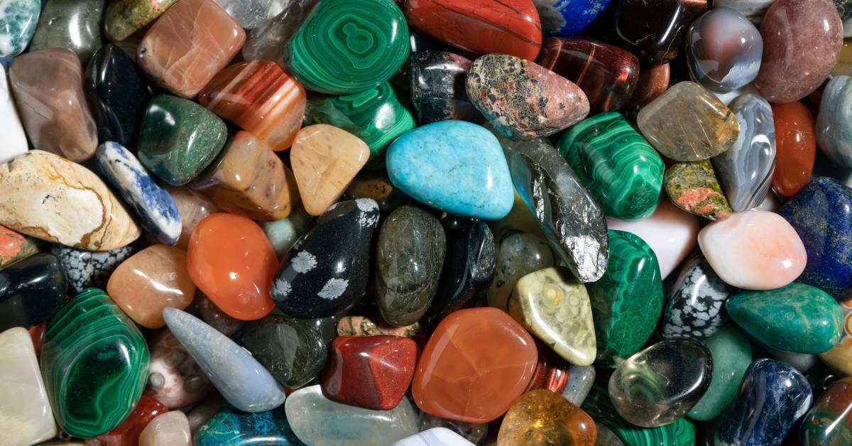 Aerial view of multiple types of polished rocks in green, blue, brown, black, yellow, and white colors mixed together.