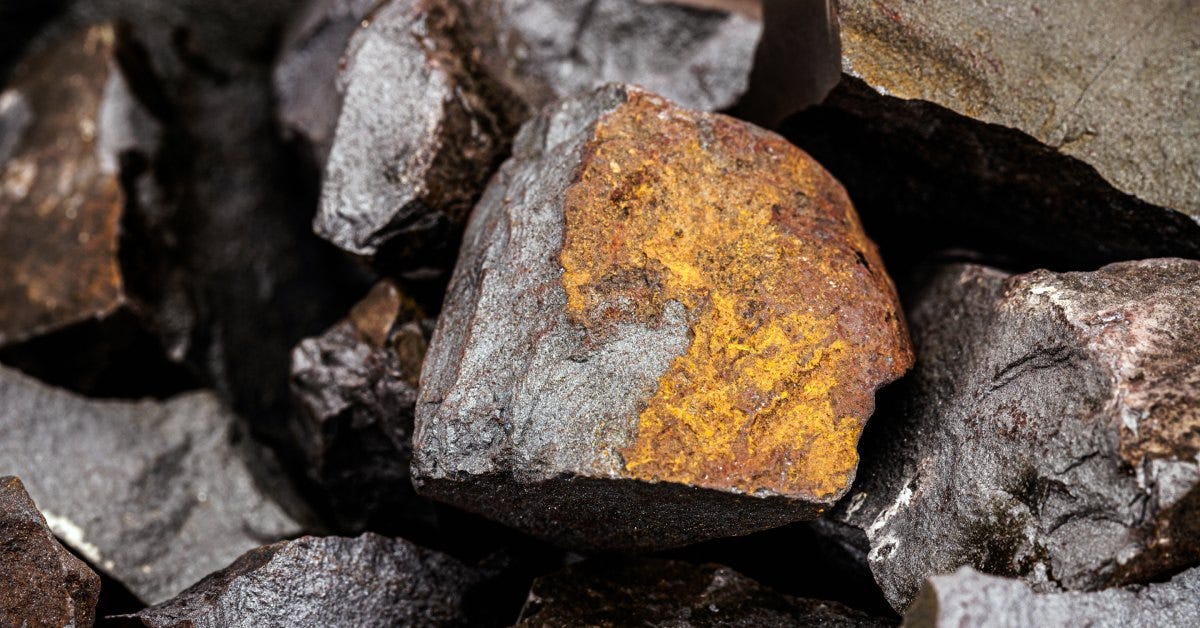 Close-to multiple black hematite rocks piled on top of each other displaying yellow, brown, and oragen tones.